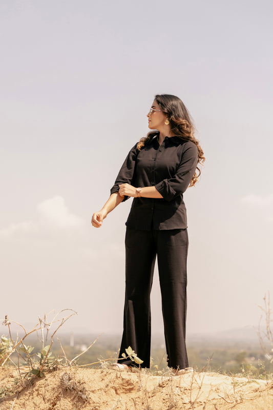 Woman in black outfit standing on a rocky landscape with a misty background