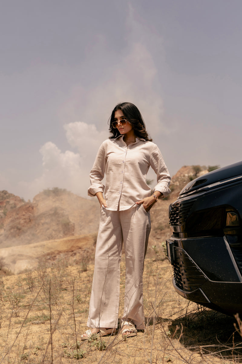 Woman standing next to a car in a desert-like landscape