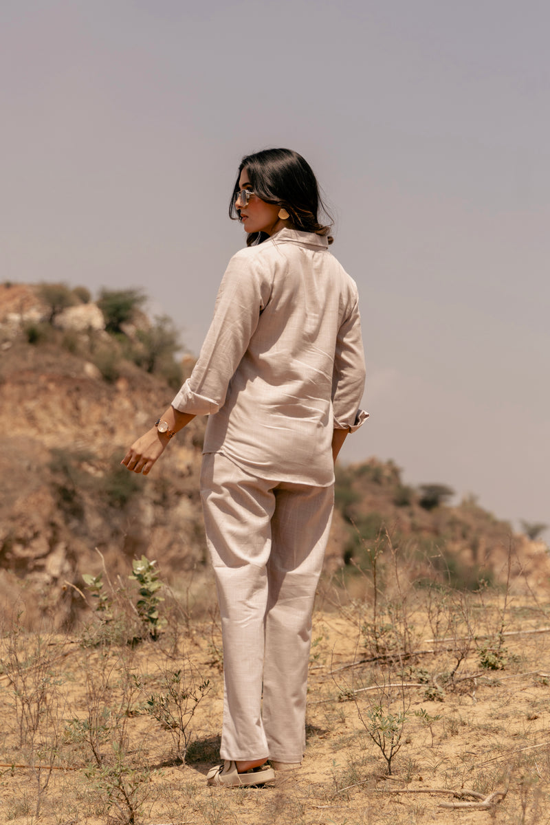 Person wearing a beige outfit standing in a desert landscape