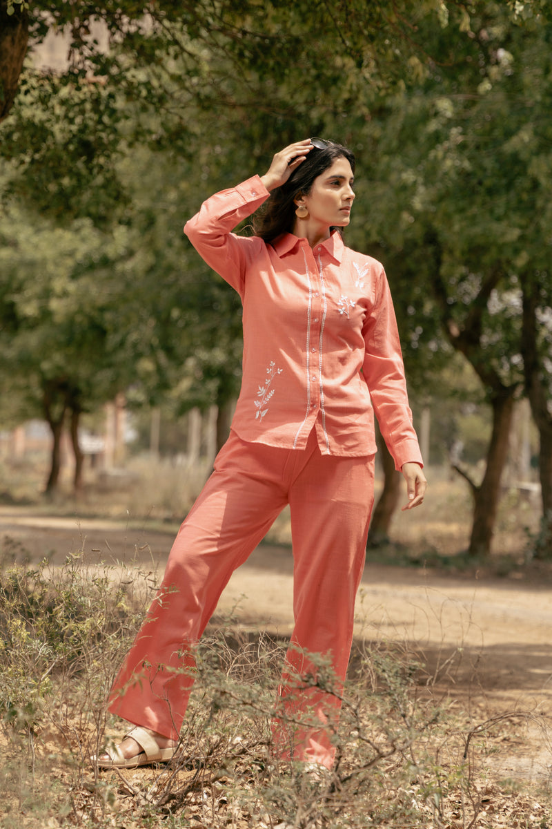 Woman in a peach outfit standing outdoors with trees in the background
