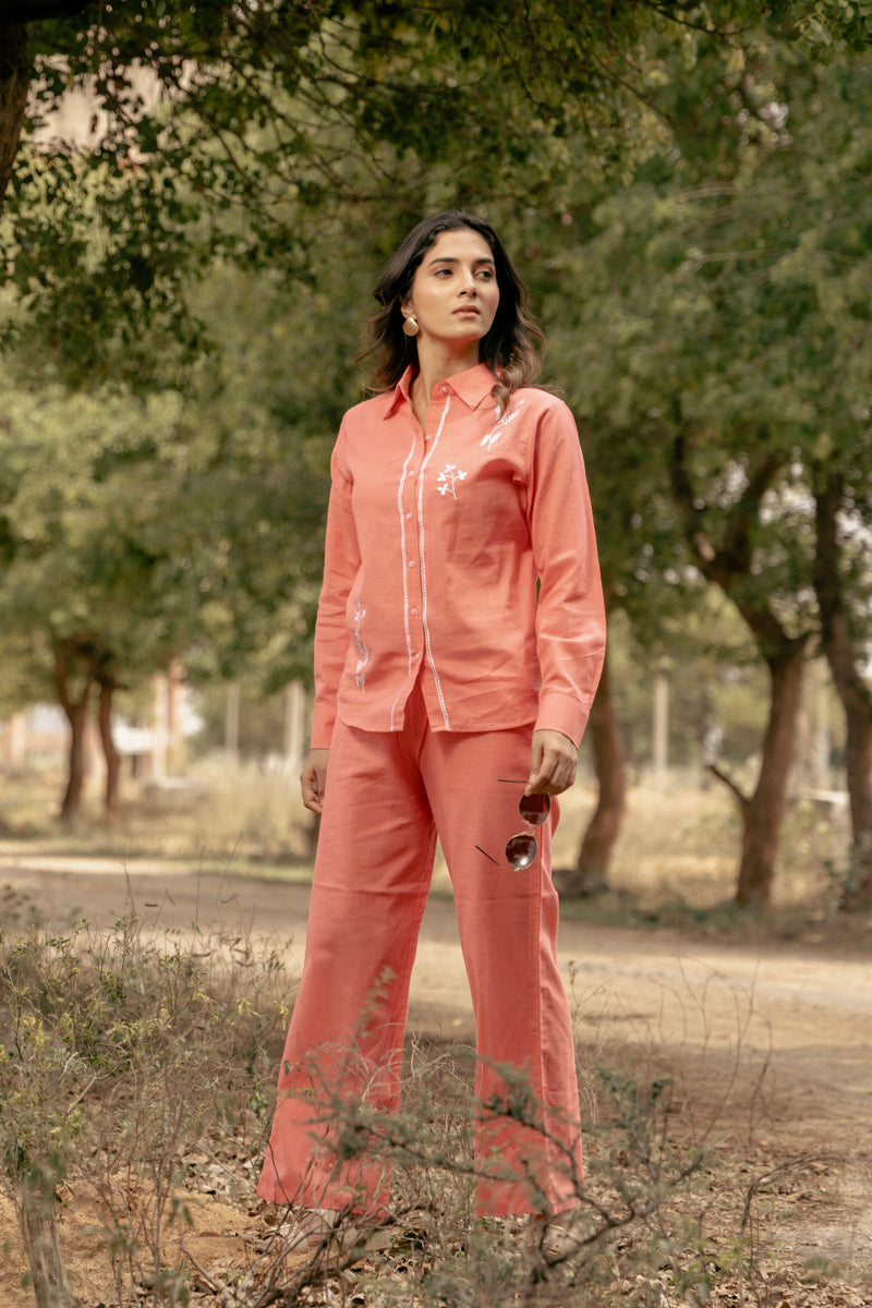 Woman in a pink outfit standing outdoors with trees in the background