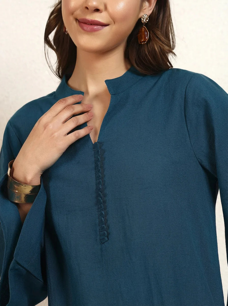 Woman wearing a blue top with a close-up of the neckline on a beige background