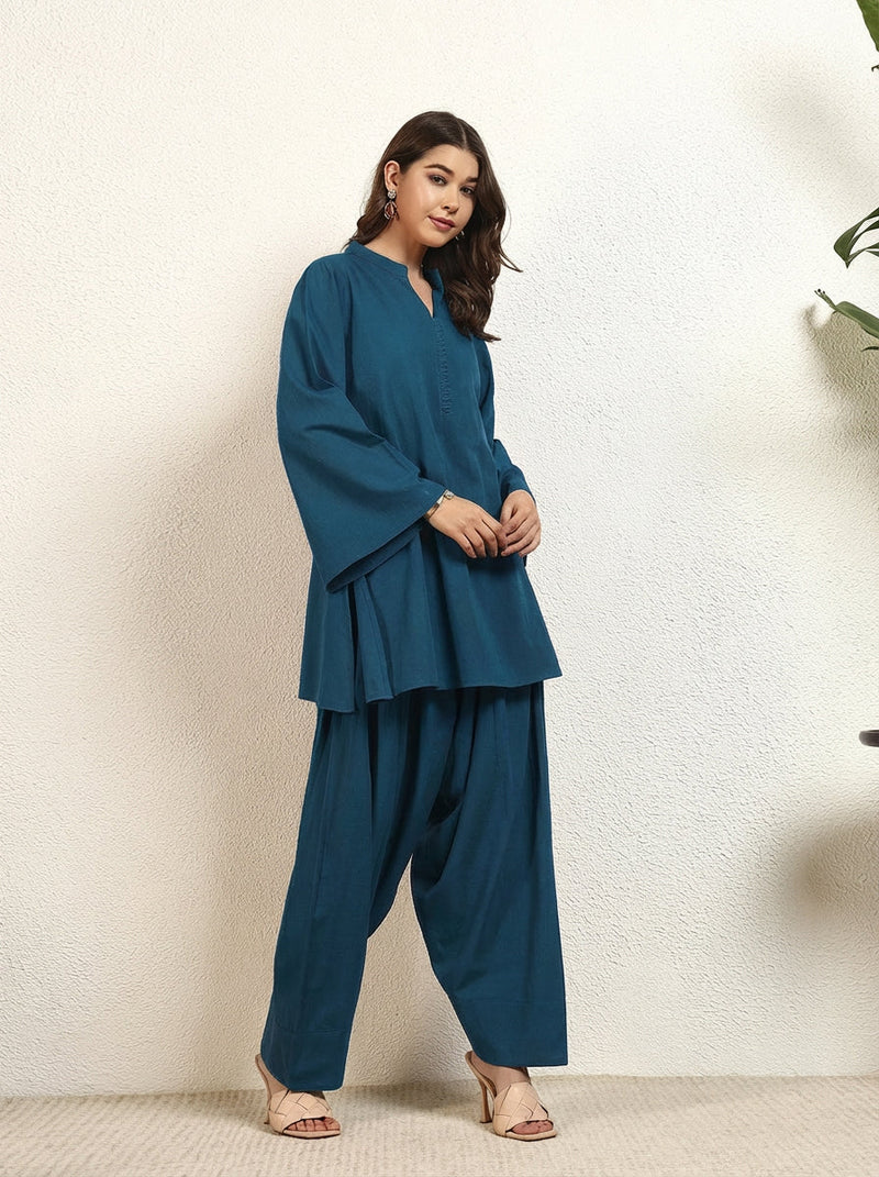 Woman wearing a teal outfit against a white background