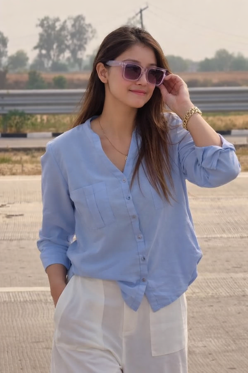 Woman wearing a light blue shirt and sunglasses outdoors
