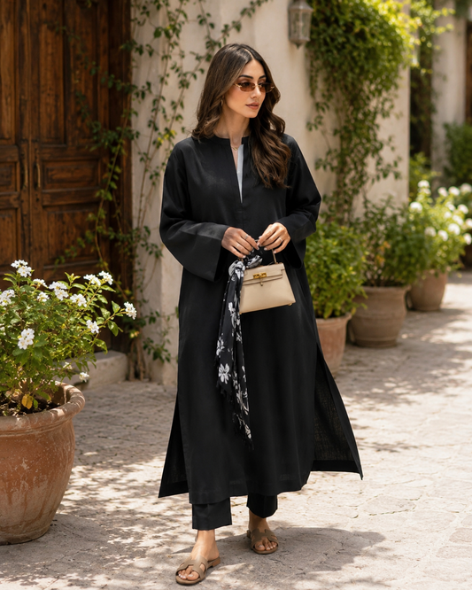 Woman in a black outfit standing outdoors with plants and flowers around