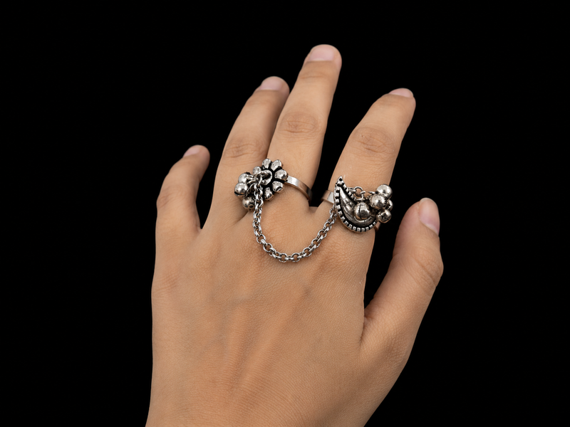 Hand wearing two silver rings on a black background