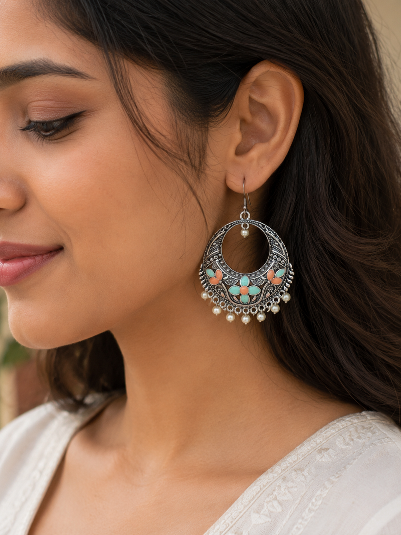 Close-up of a woman wearing an ornate earring with turquoise stones and pearl-like beads.