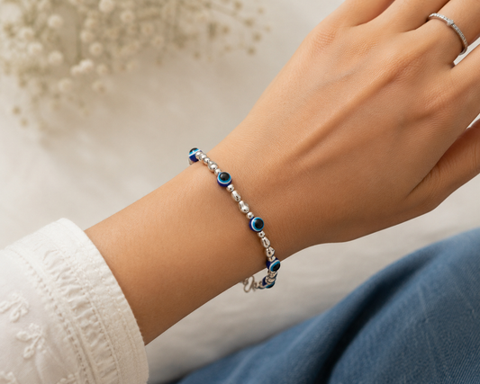 Close-up of a wrist wearing a bracelet with blue beads on a neutral background