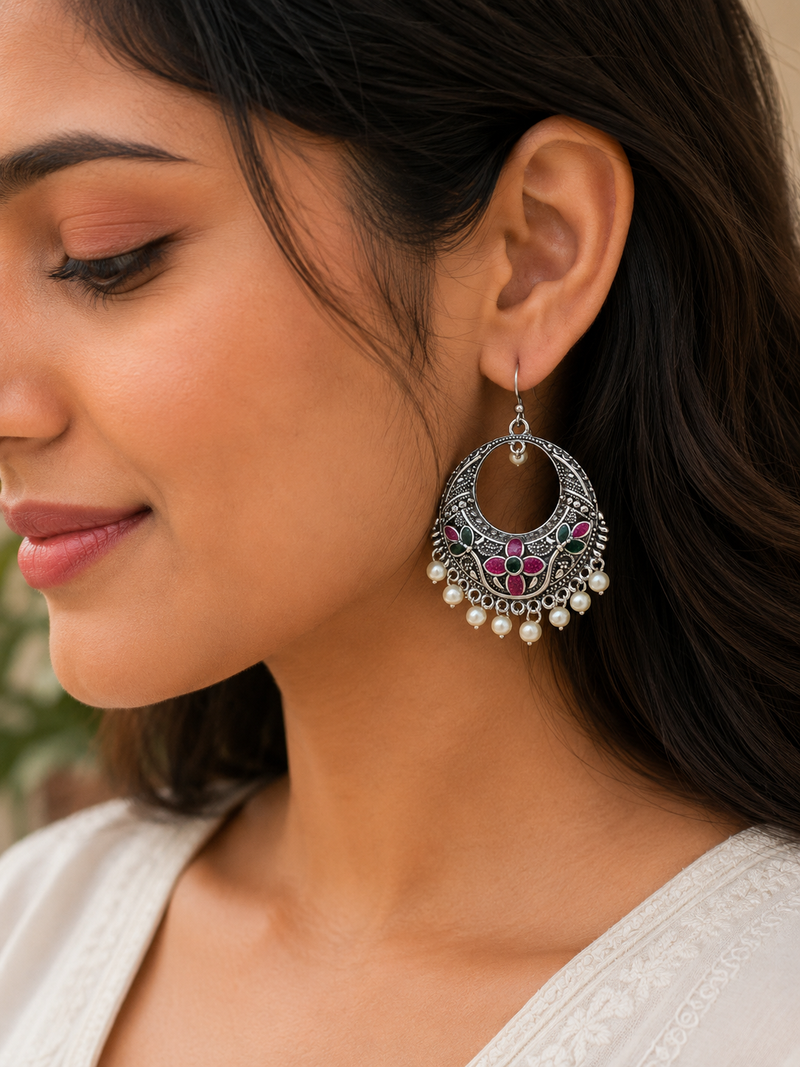 Close-up of a woman wearing a decorative earring with pearls and gemstones.