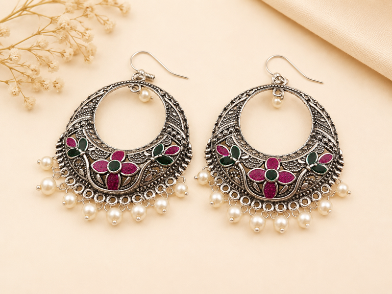 Ornate earrings with floral designs and pearl-like beads on a beige background
