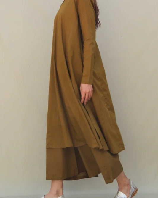 Person wearing a long brown dress against a plain background