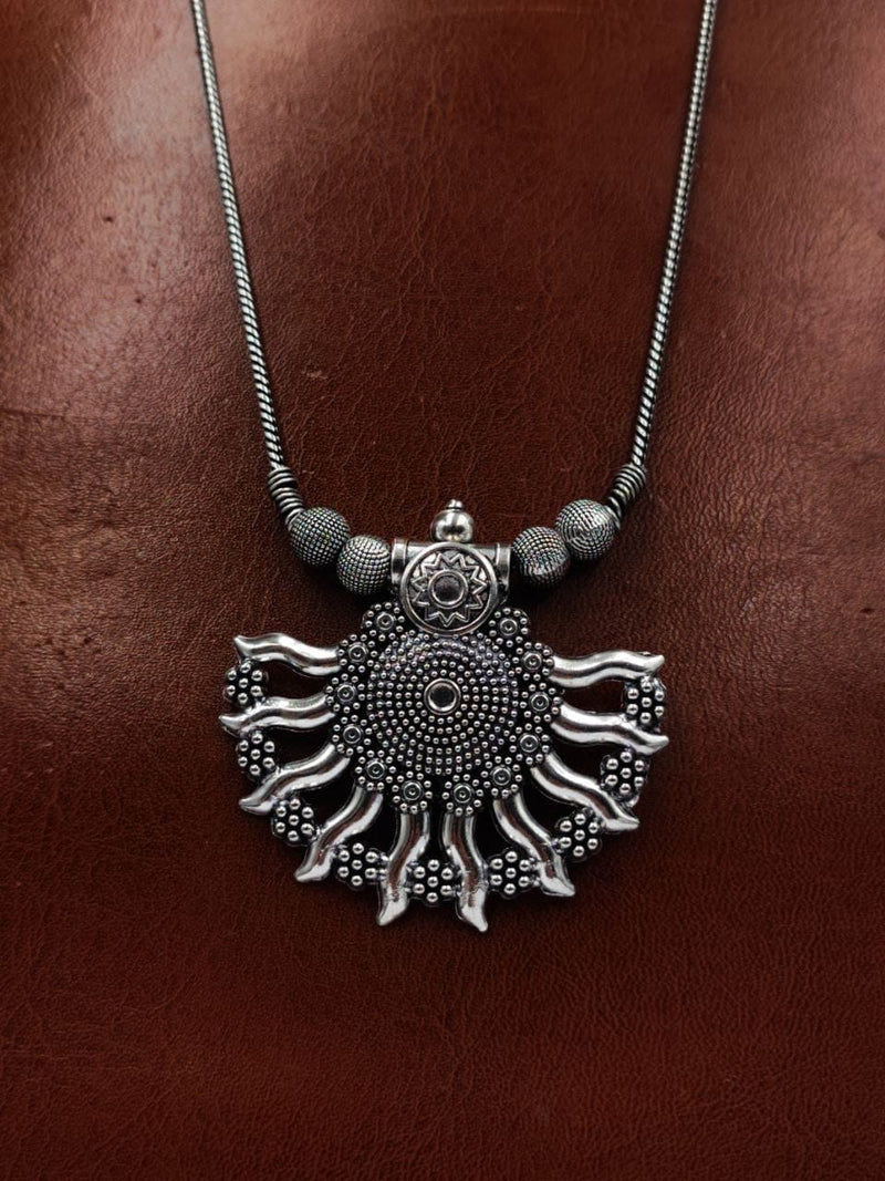 Silver necklace with a decorative pendant on a brown leather surface