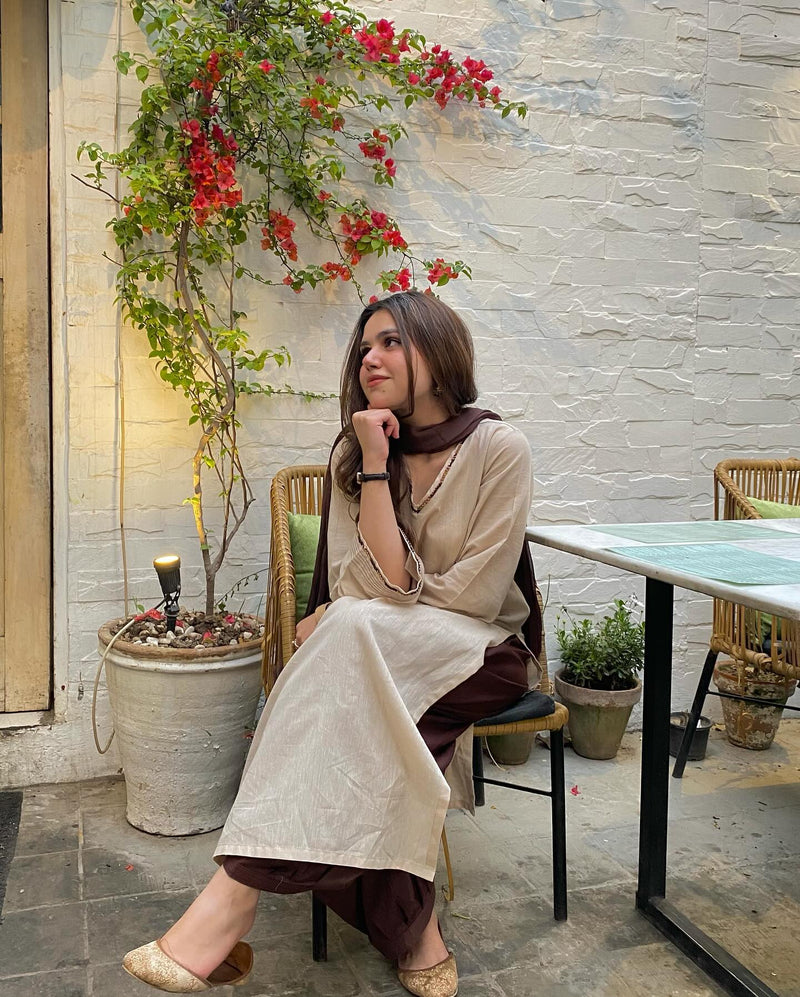 Woman sitting at a table in an outdoor cafe with flowers and plants around.