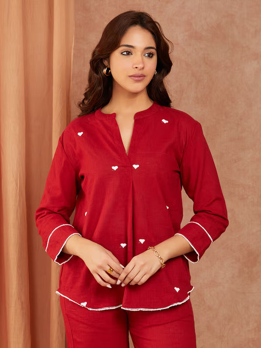 Woman wearing a red outfit with white heart patterns against a brown background